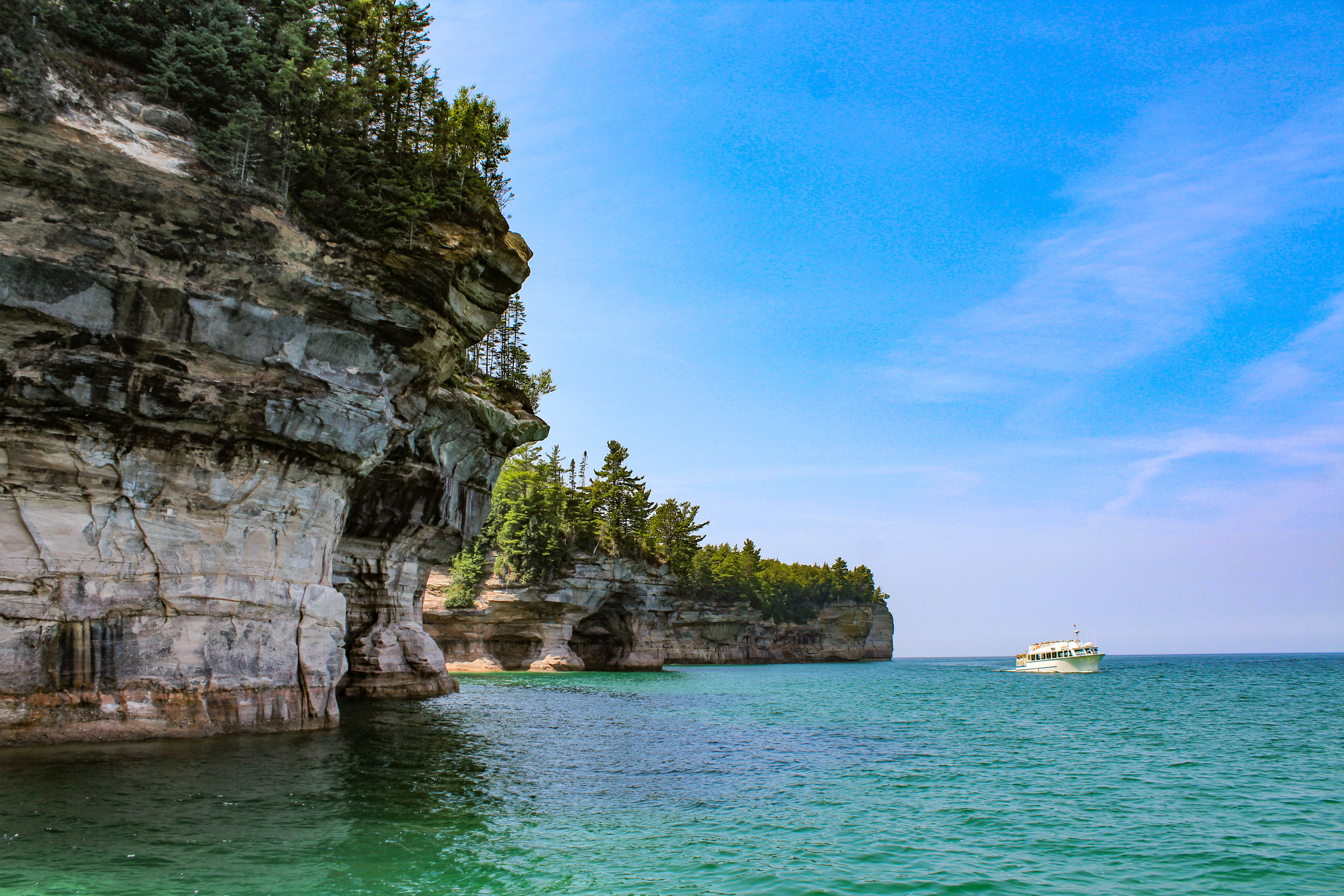 Passenger boat near tall cliffs above a lake