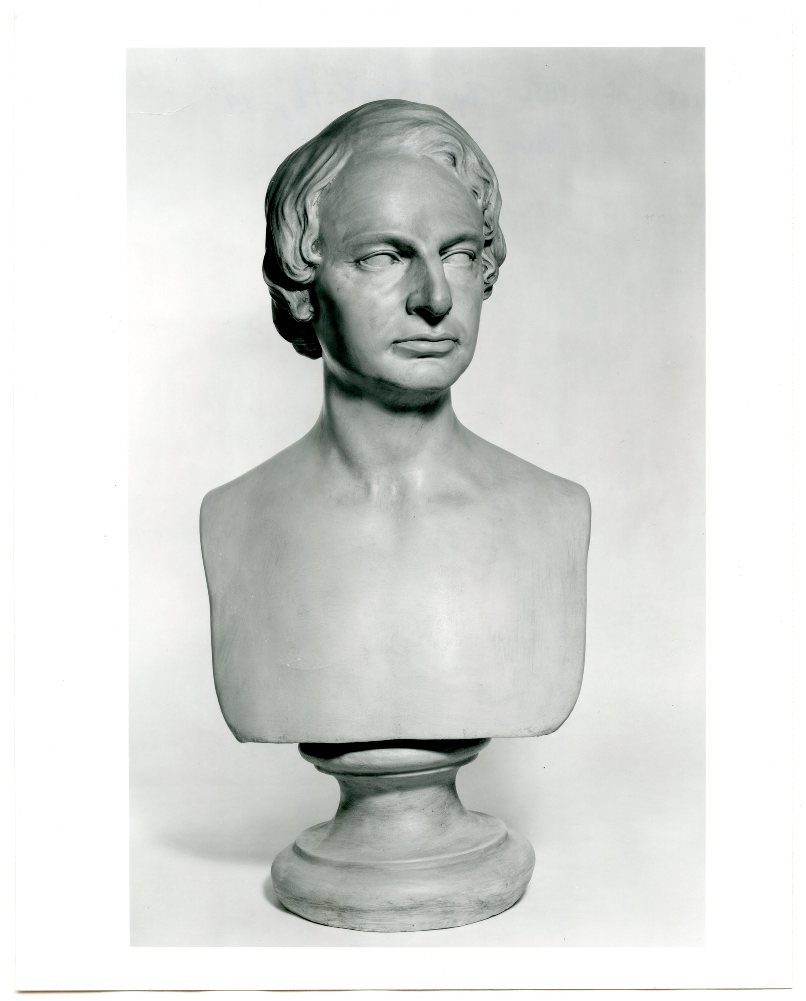 Black and white photograph of a bust of young Henry Wadsworth Longfellow. He has ear-length hair and is sculpted nude.