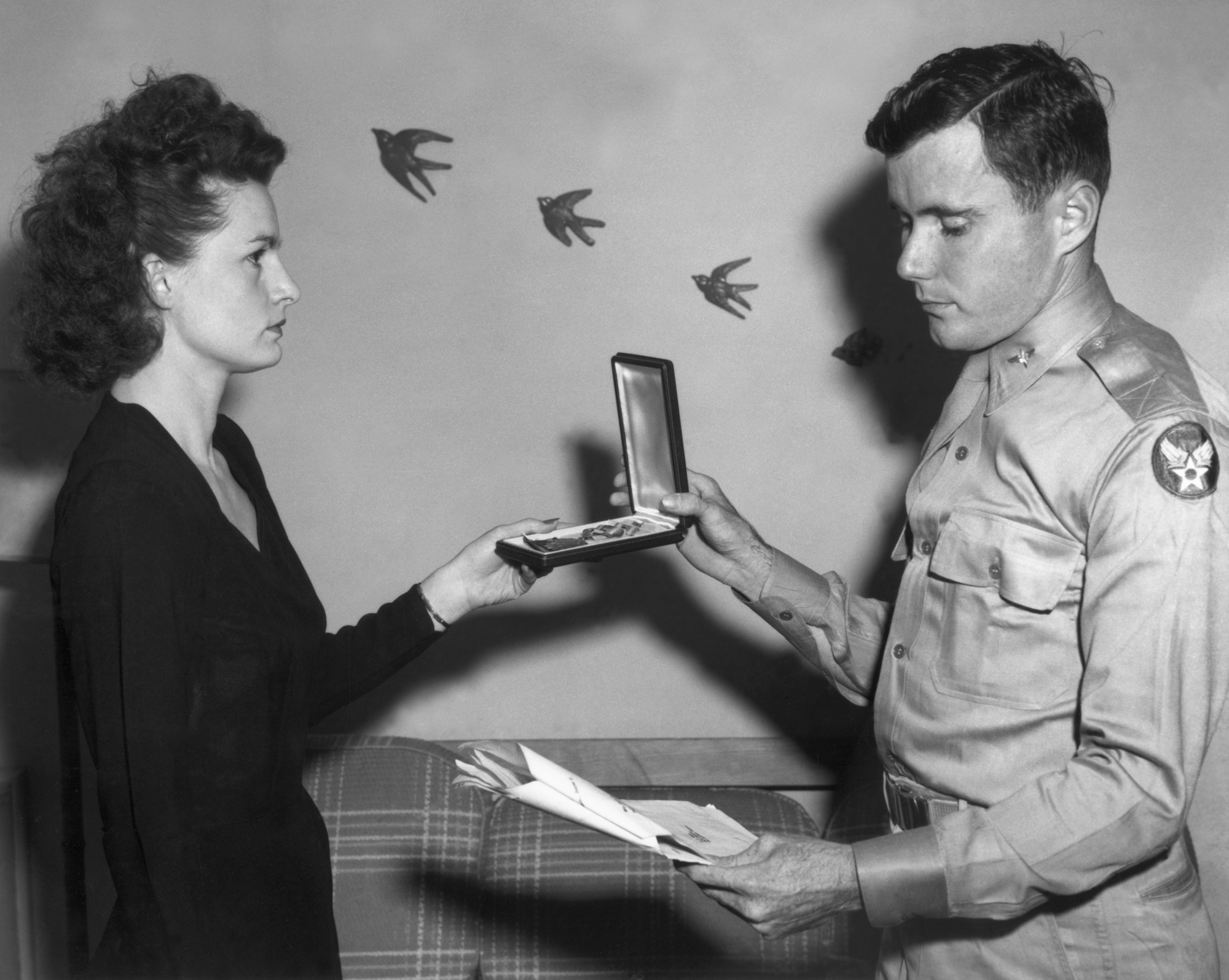 A man looking at some papers hands a medal to a solemn looking woman. 