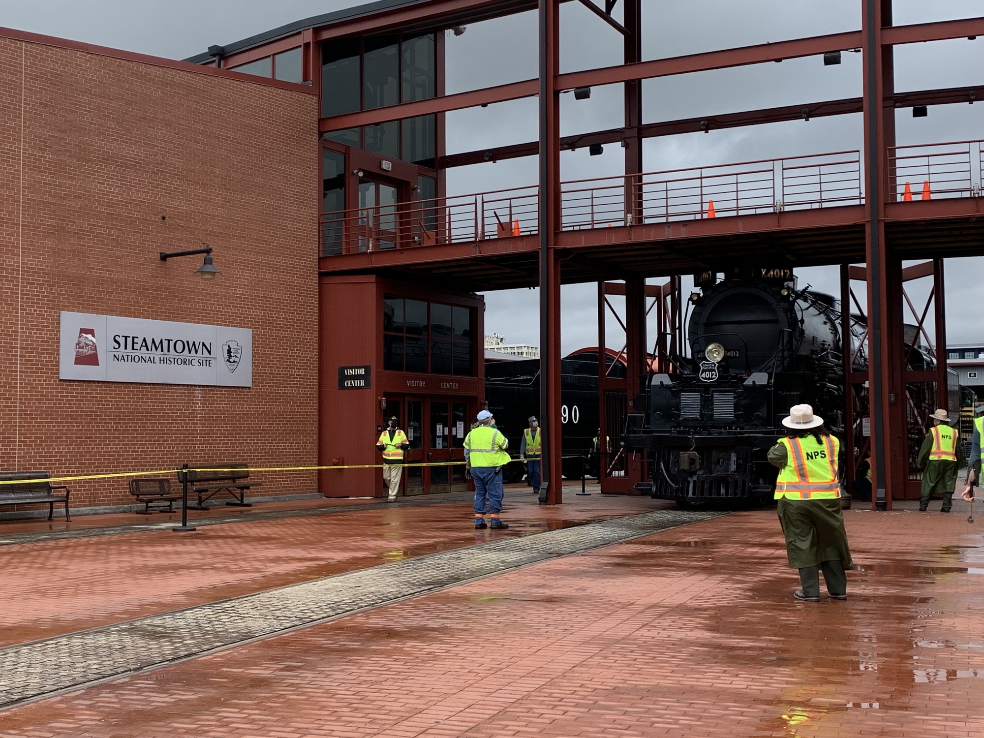 Brick building with sign reading Steamtown National Historic Site and a large black train on a track being moved under an awning