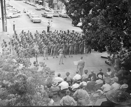 Welcome Home Ceremony for 489th Reserve Unit; crowd gathered in front of Administration
building, cars on street and parked in background on upper left corner of image. Military.
