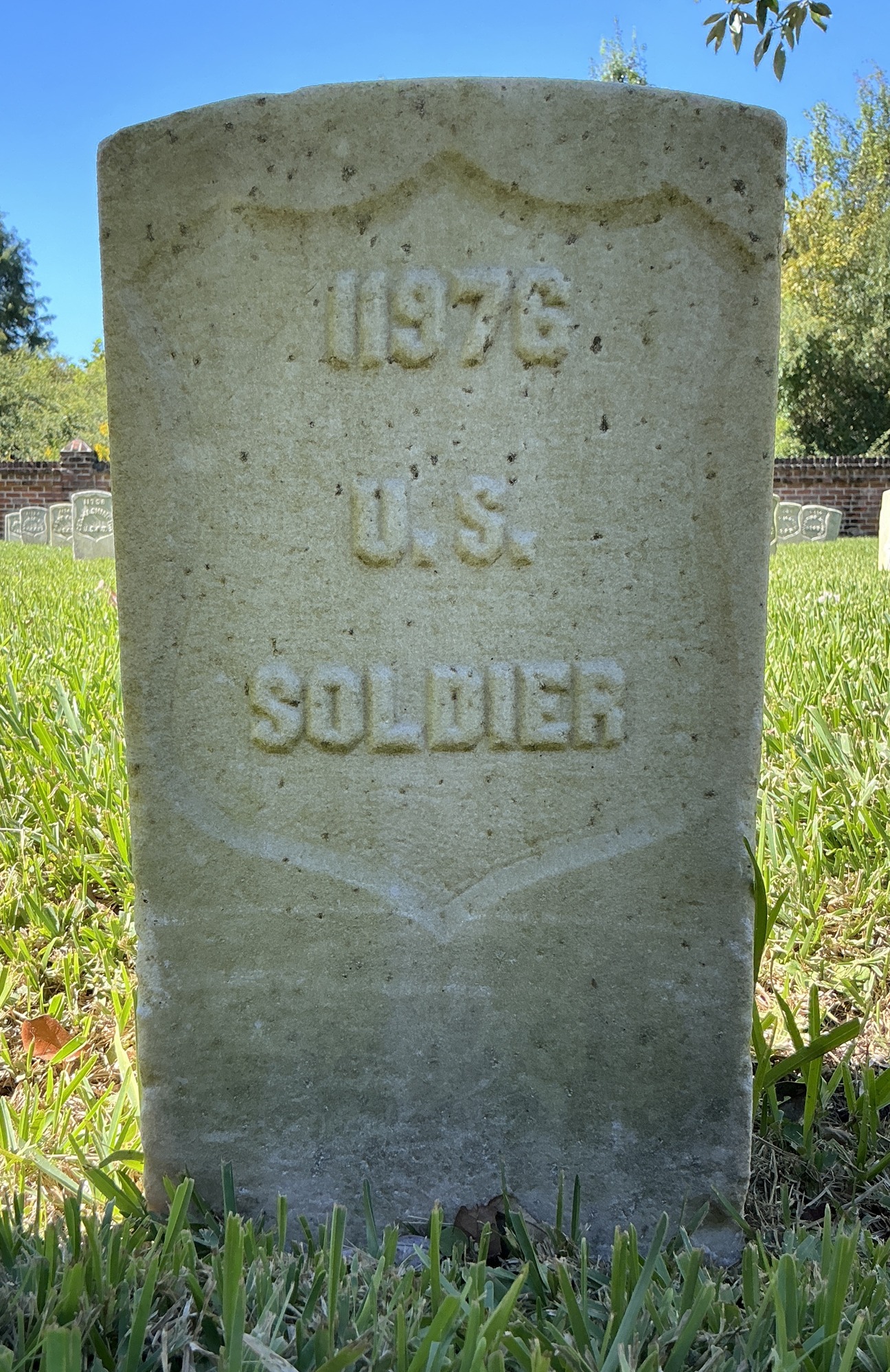 Front of historic upright marble headstone with recessed shield face.