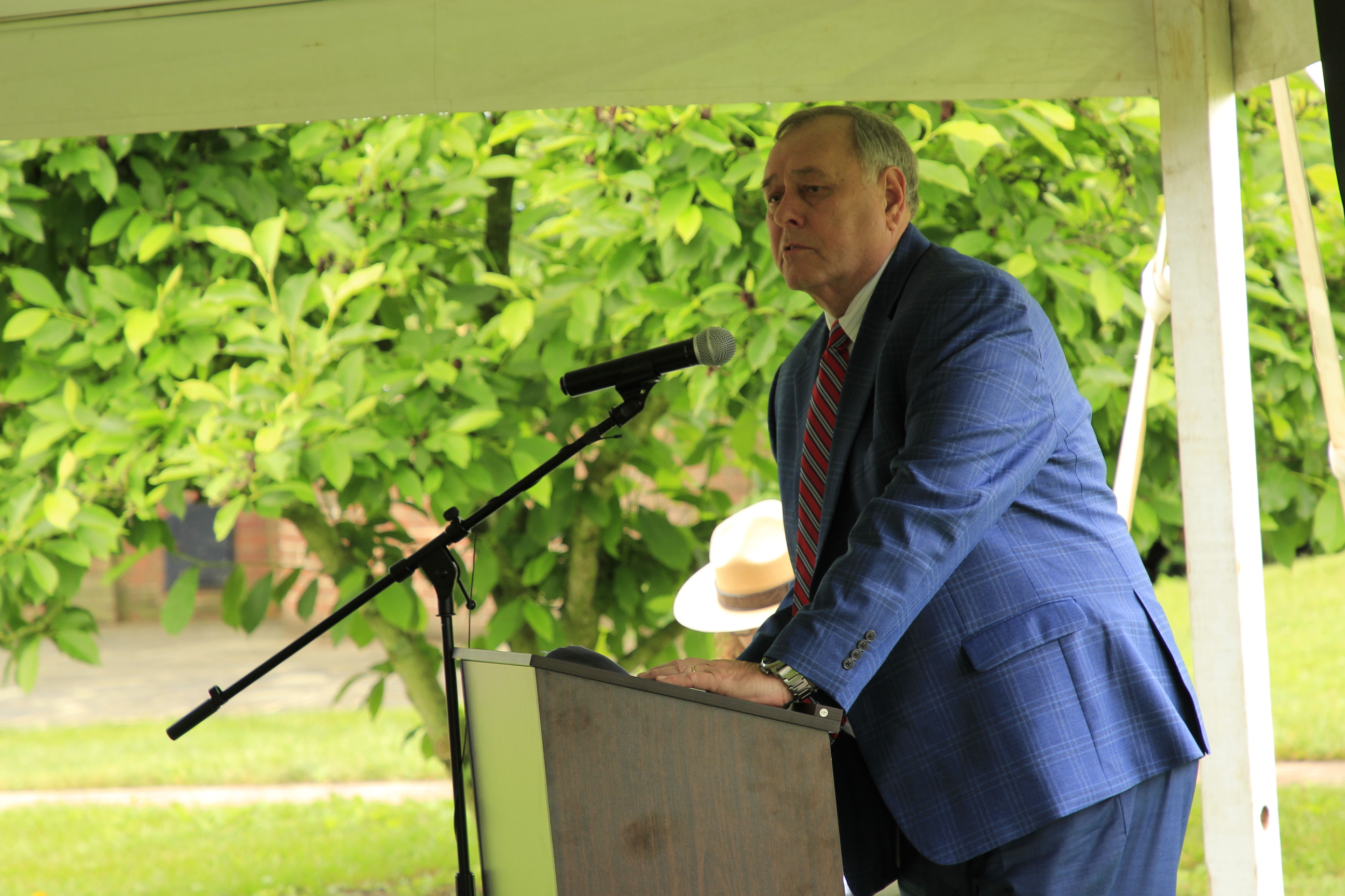 A man in a blue suit stands and speaks at a podium. 