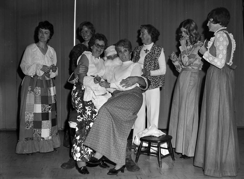 Christmas holiday party, 1976. Two women sit on Santa's lap on stage in Visitor Center auditorium.