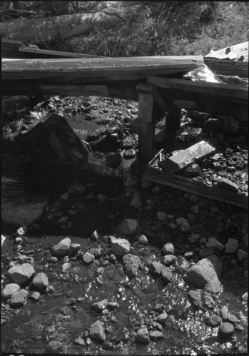 Sugar Pine flume showing how water is wasted into stream from leaky dirt dam & poor flume.