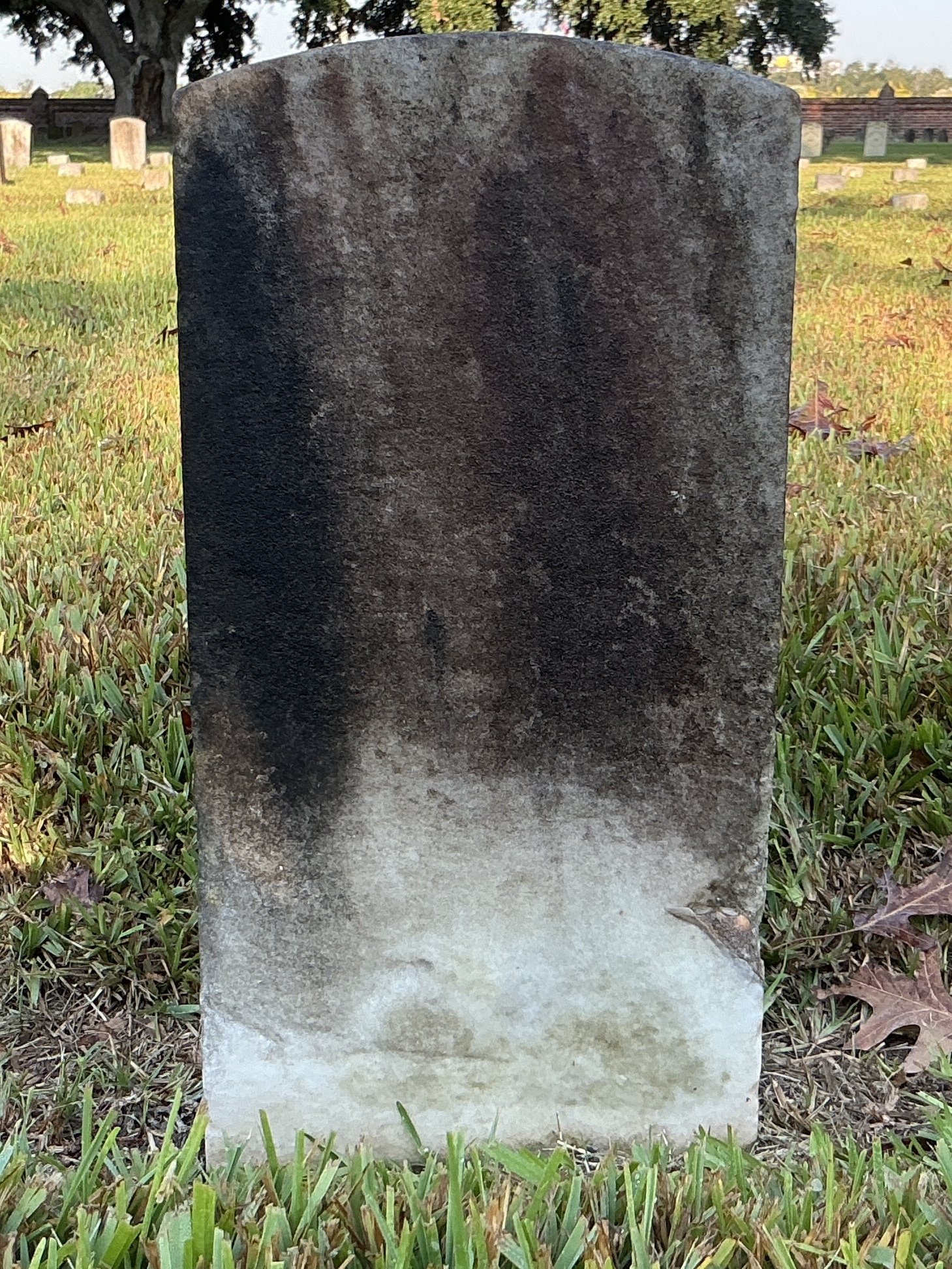 Back of historic upright marble headstone with recessed shield with recessed lettering face.