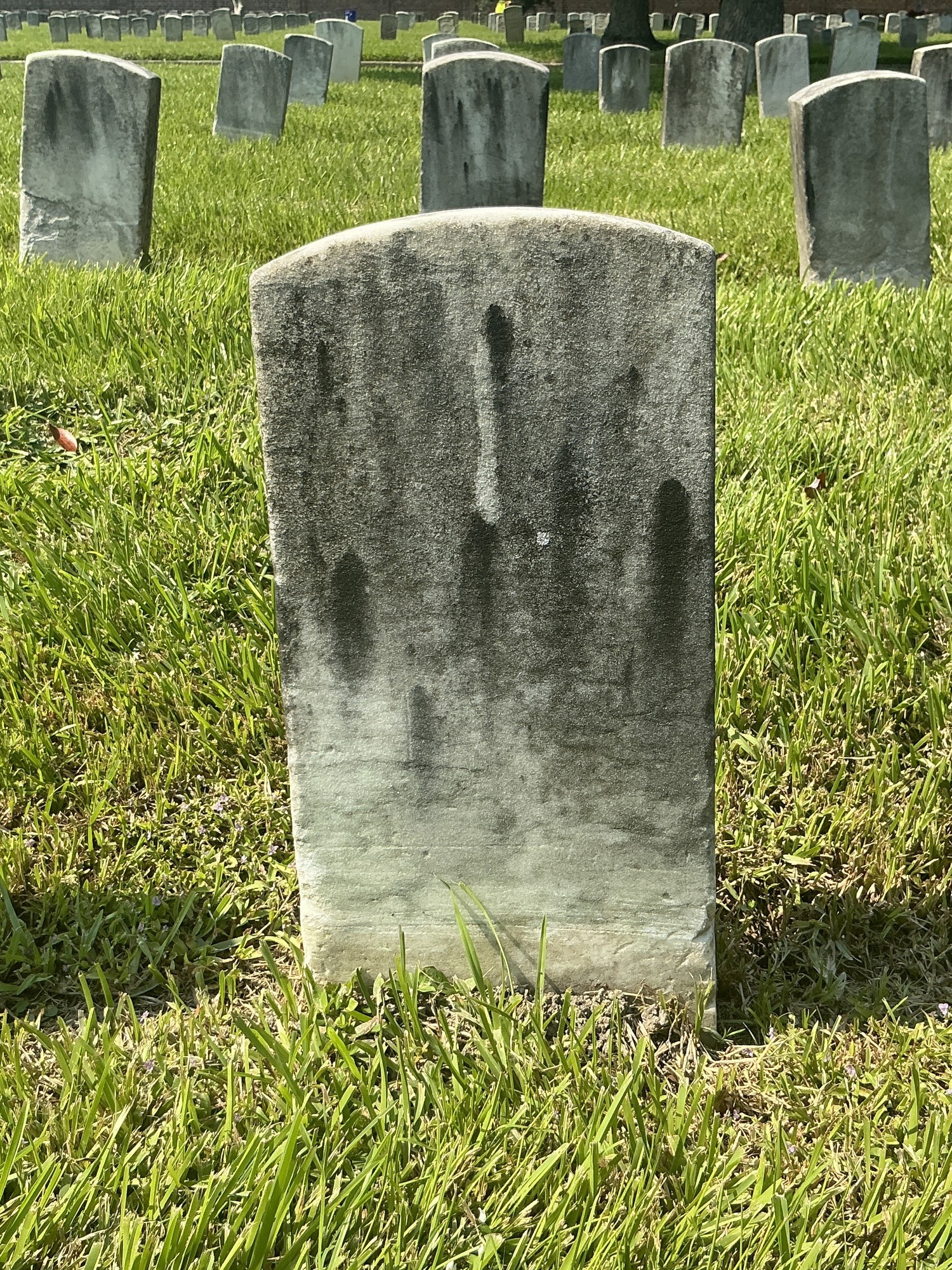 Back of historic upright marble headstone with recessed shield face.