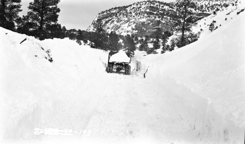 Snowstorm blocking highway, truck carting away drifted snow.