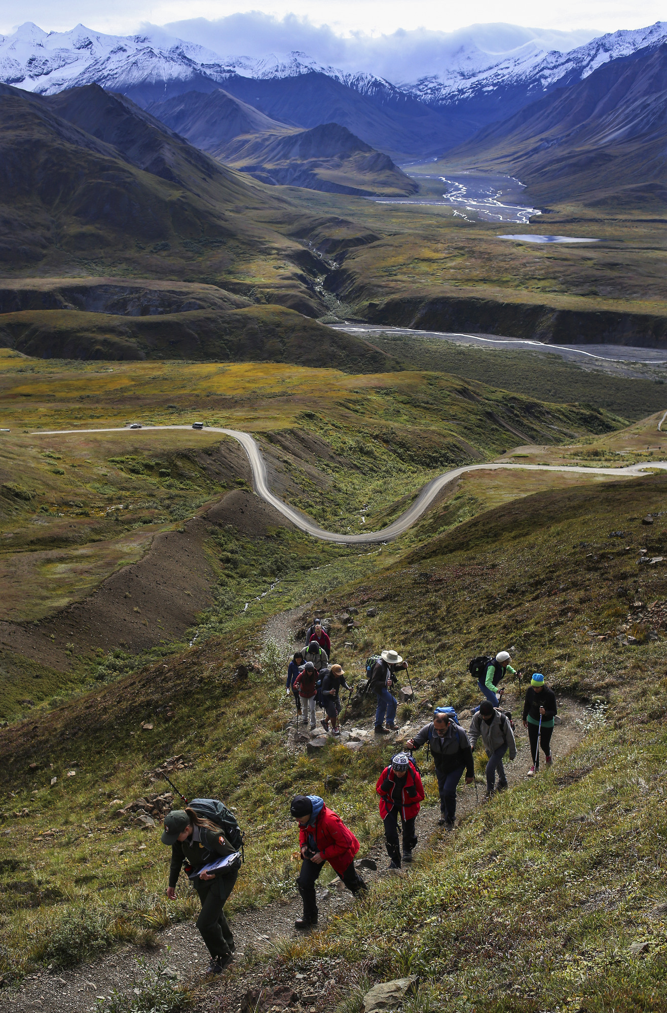 a ranger leads a group of twelve people on a hike up a mountain trail