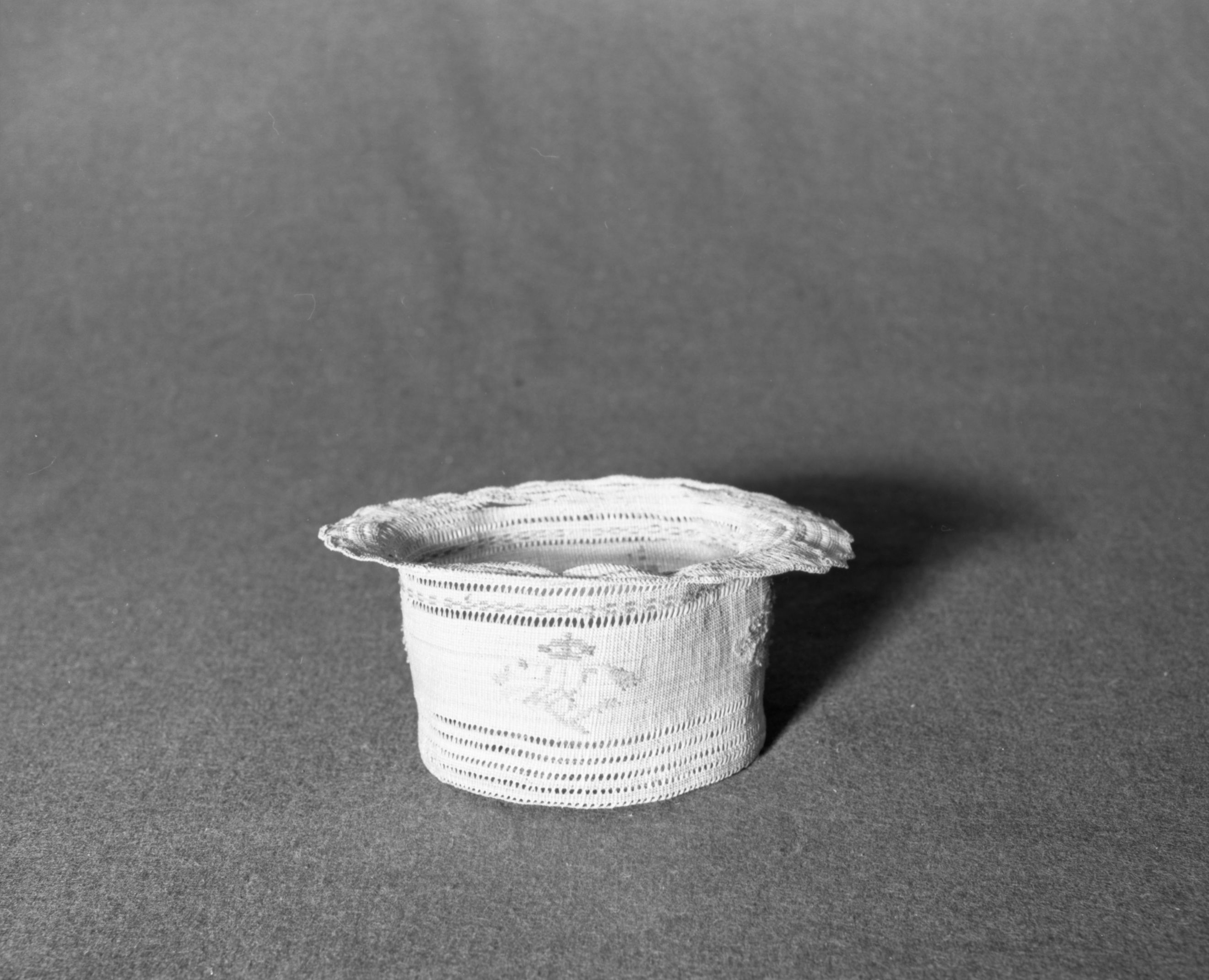 Marie Rozier Collection, Catalog No. 9. Object: Aleut hat. Dimensions: 5" x 3 1/2". Materials: beachgrass, commercial colored floss. Technology: twined, down to right slant of turns. Collection History: Gift of Ora Doyle. Photographed by Michael Dixon, December 1982. Catalogued by Craig Bates and Barbara Beroza. Yosemite Collections, National Park Service.