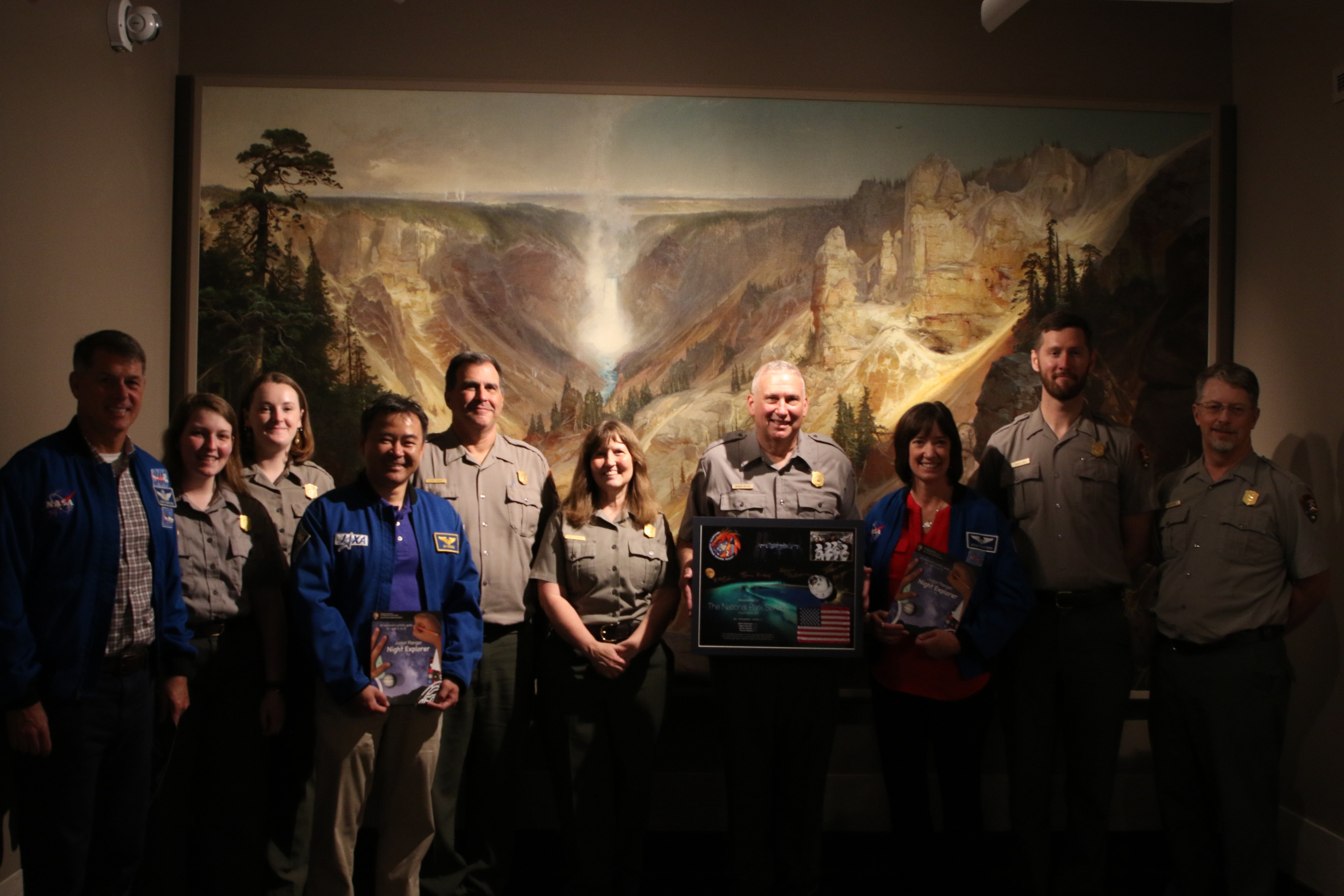 Astronauts and NPS staff in front of a painting.