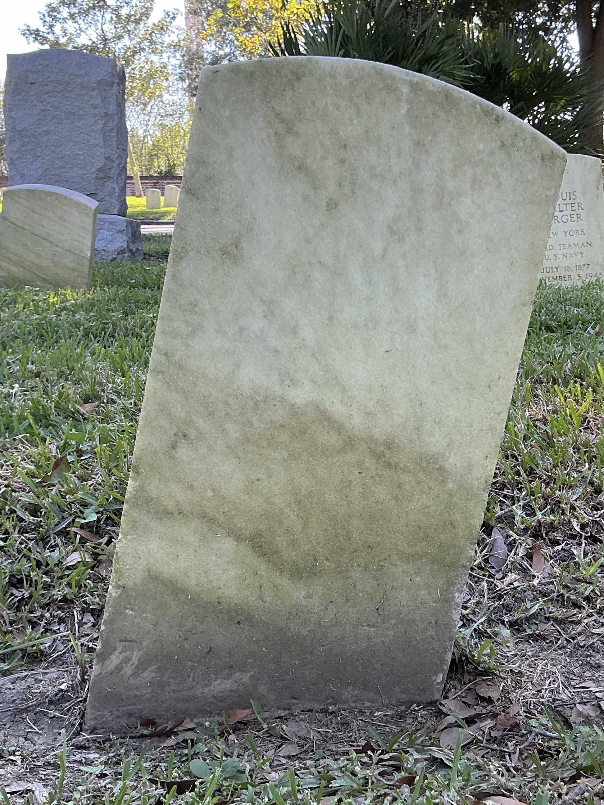 Back of historic upright marble headstone with recessed shield face.