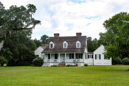 Historic white farm house with a prominent porch and two attached wings