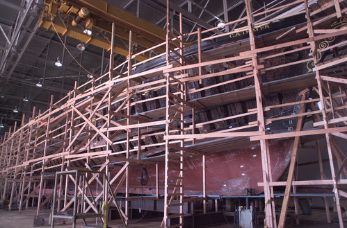 The wooden hull of a large vessel covered with scaffolding.
