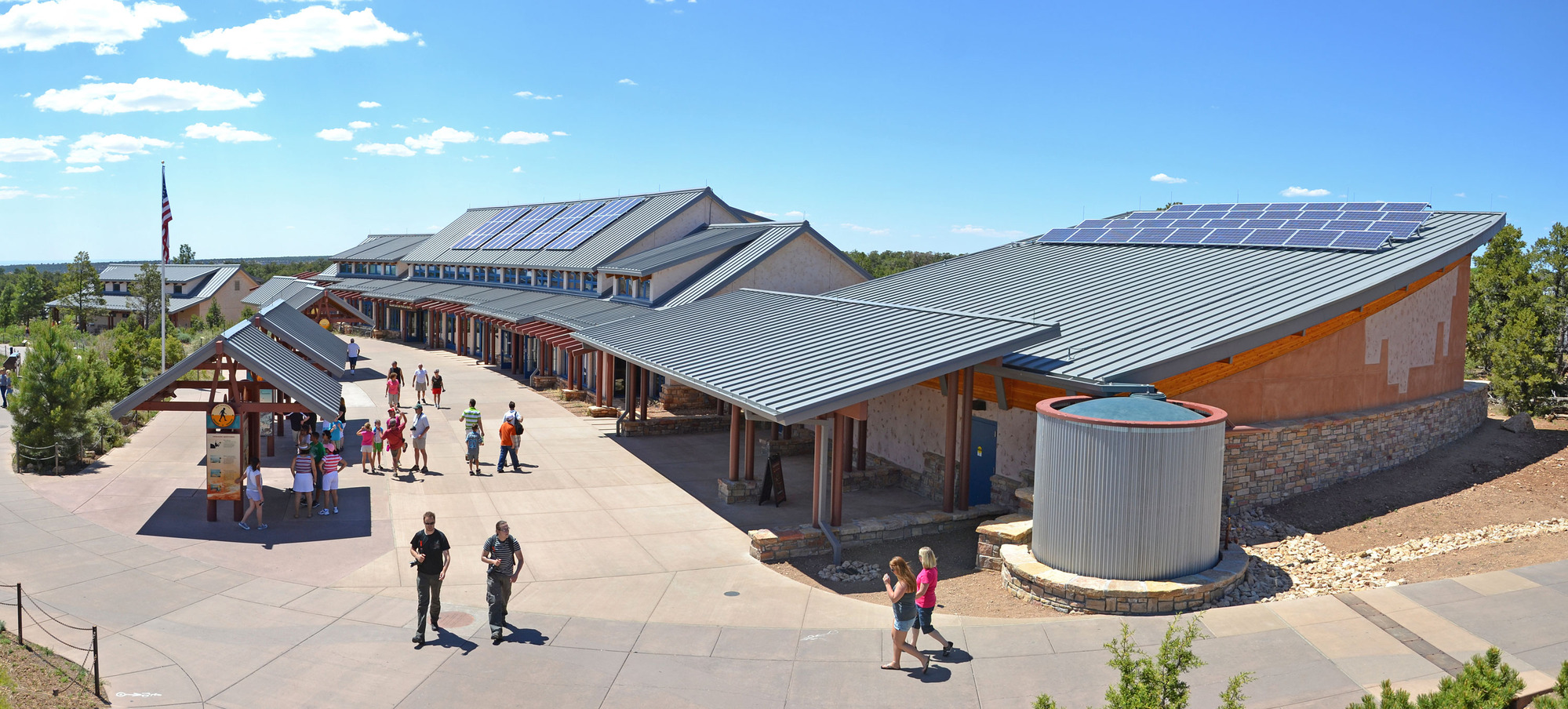 Several green-roofed buildings in front of pedestrian plaza -- most featuring solar panels. A round cistern drains the corner of one roof