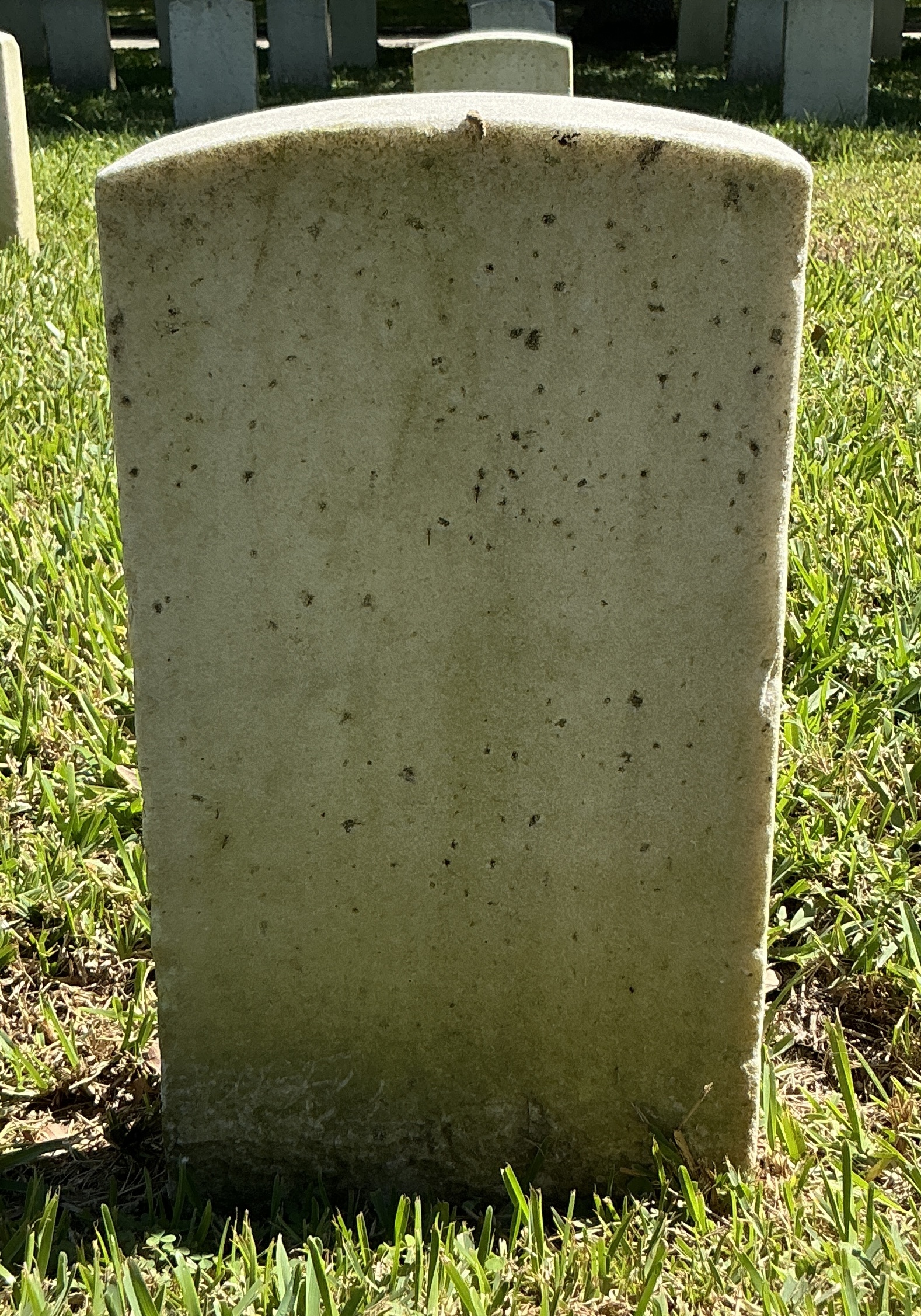 Back of historic upright marble headstone with recessed shield face.