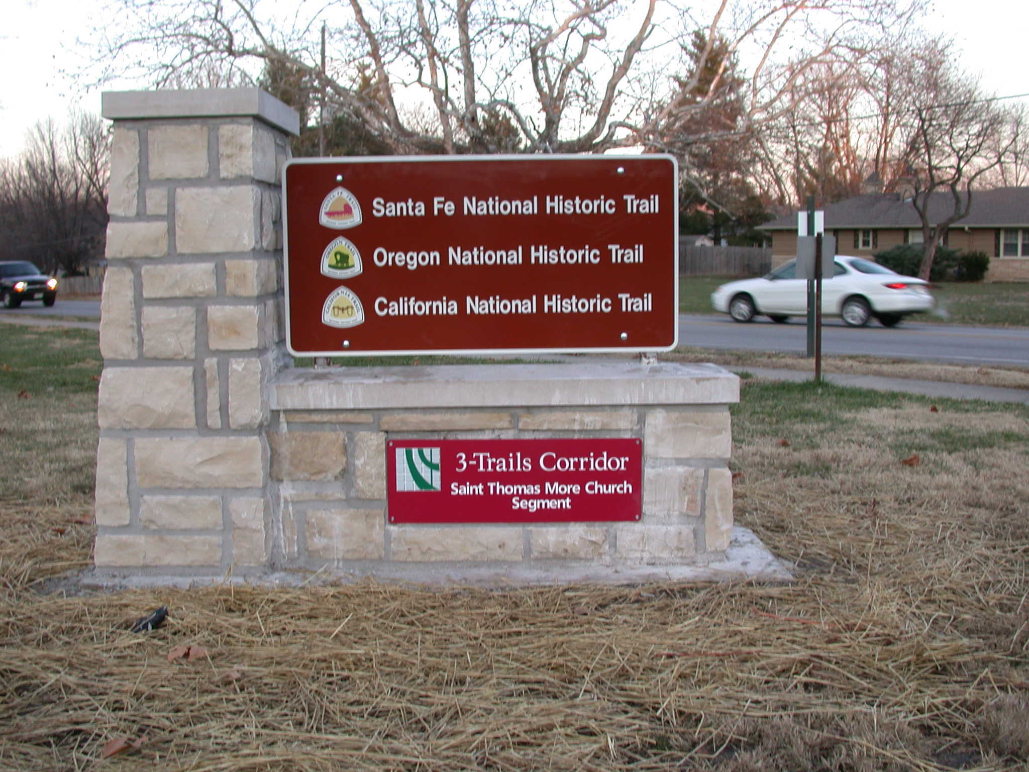 A signboard with the text "3 trails corridor" on it and car in the background.