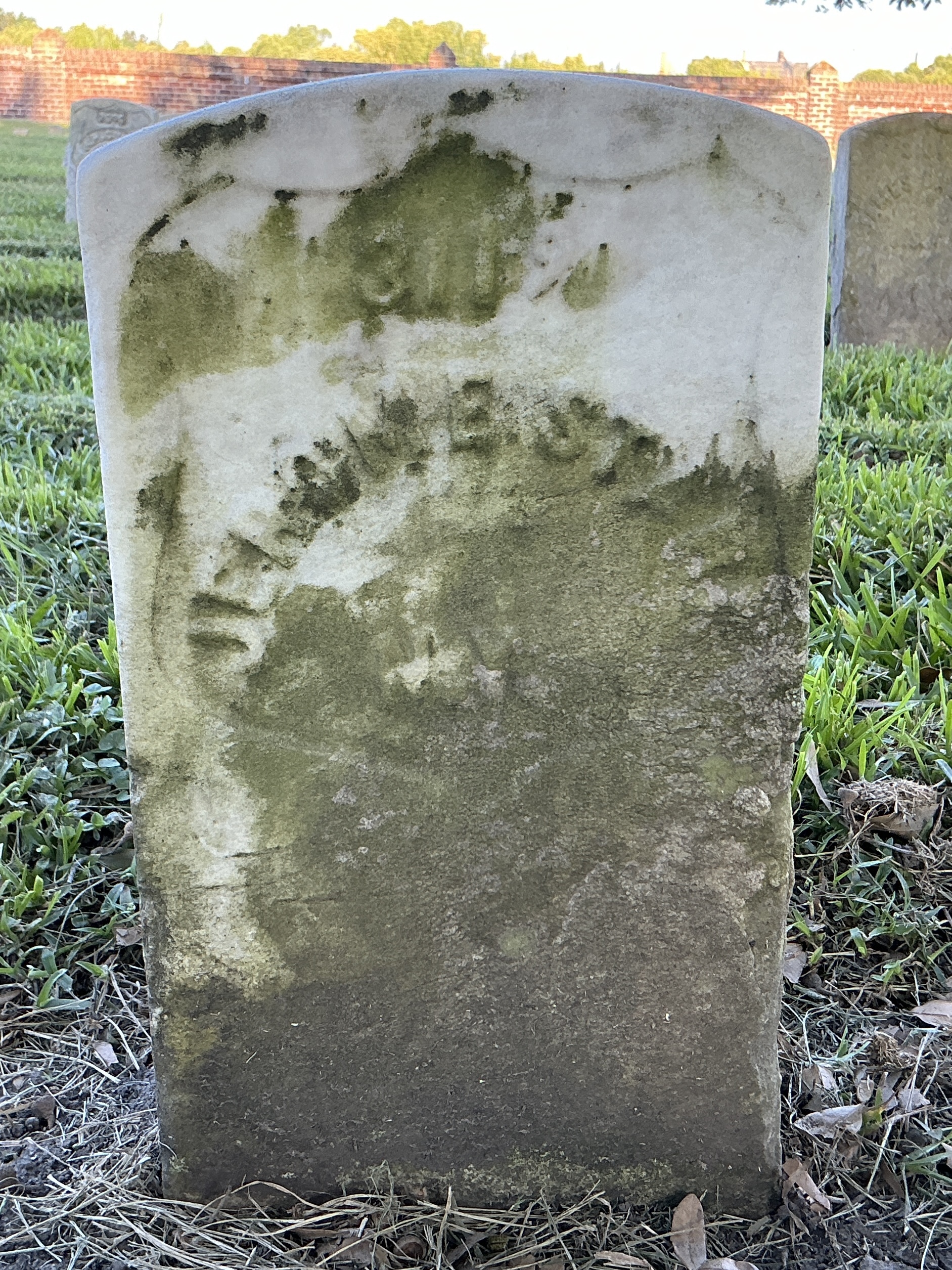 Front of historic upright marble headstone with recessed shield face.