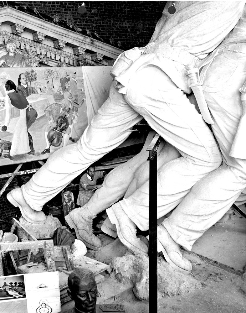 A man uses a cutting ring to sculpt leg muscles on a plaster figure