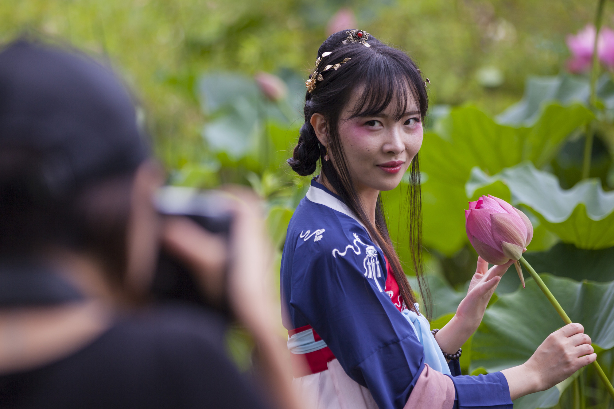 A woman poses for a photo with a lotus flower. 