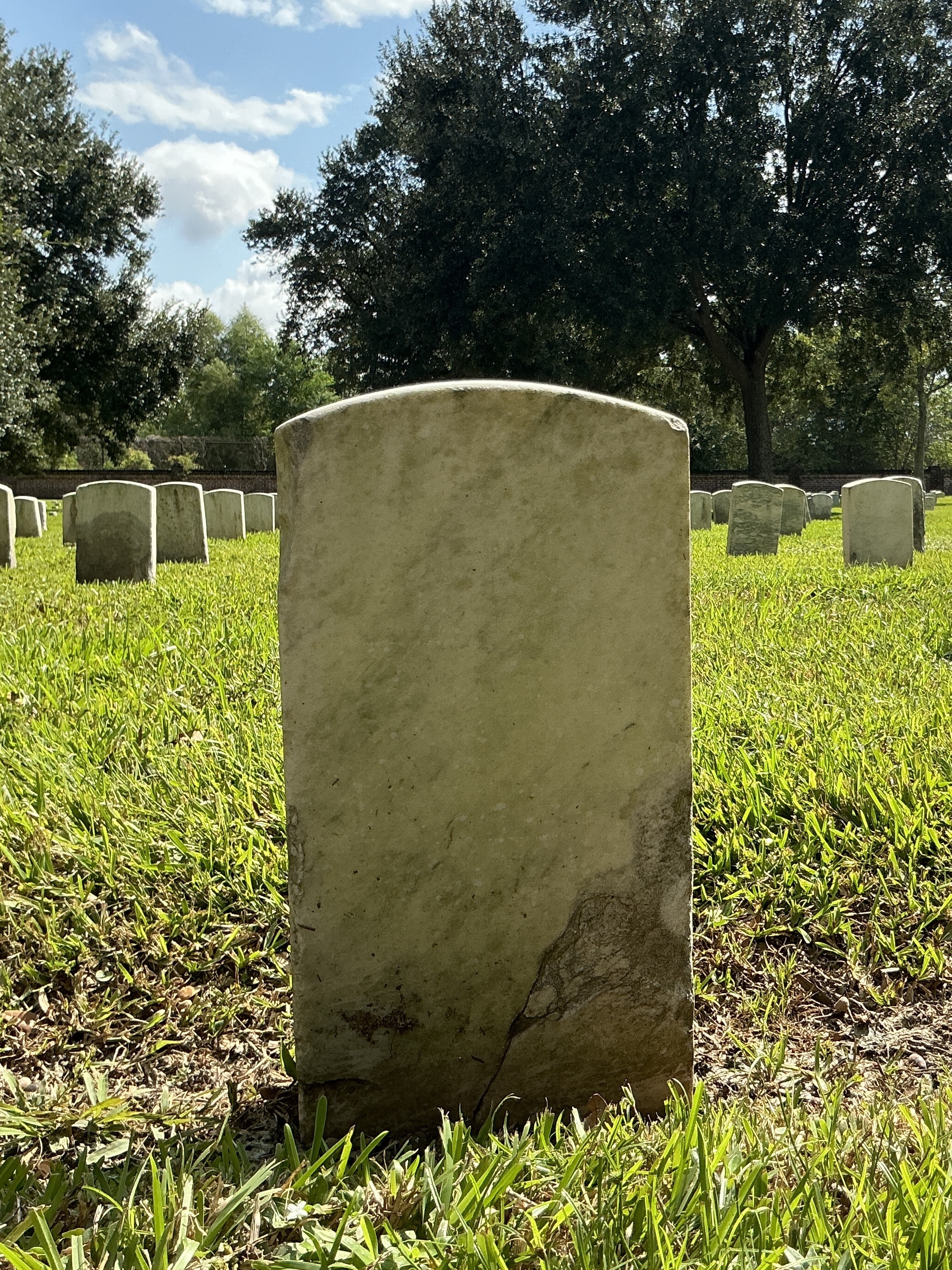 Back of historic upright marble headstone with recessed shield face.