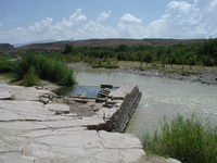 The stone foundation of a hot springs bath house remains abuts a river.