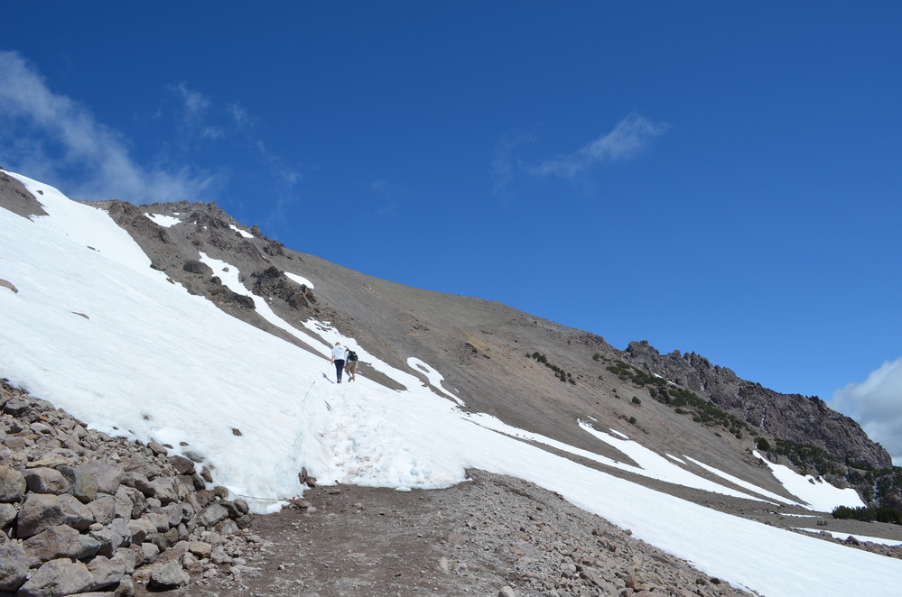 Two hikers cross a snow-covered switchback near the summimt of Lassen Peak.