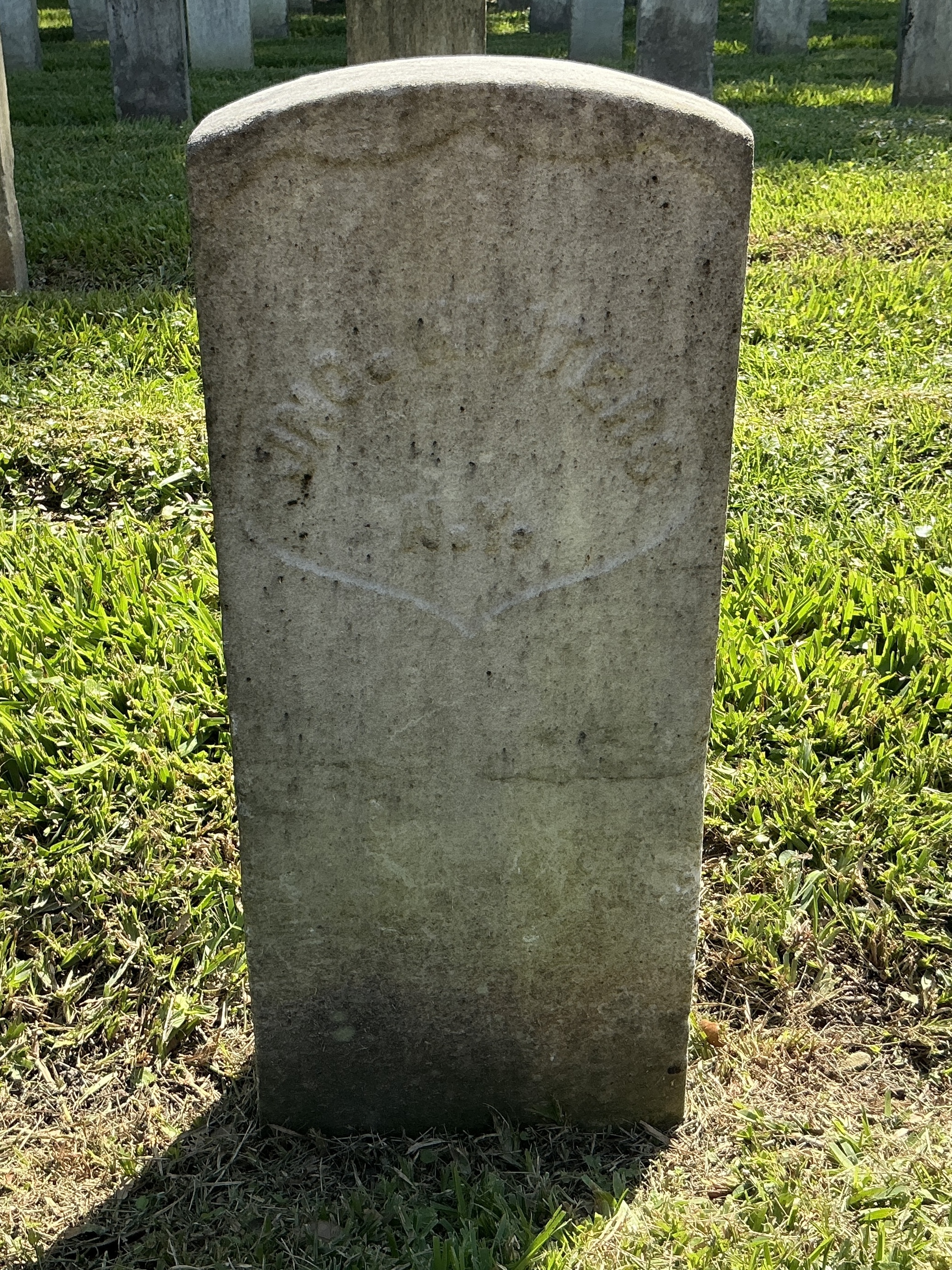 Back of historic upright marble headstone with recessed shield face.