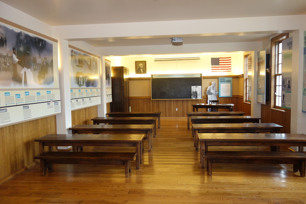 A one-room school with tables and benches. 