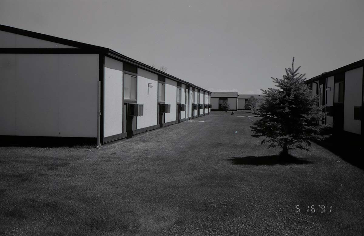 Backside of barracks with landscaping between buildings. [Image possibly for comparative housing study]
