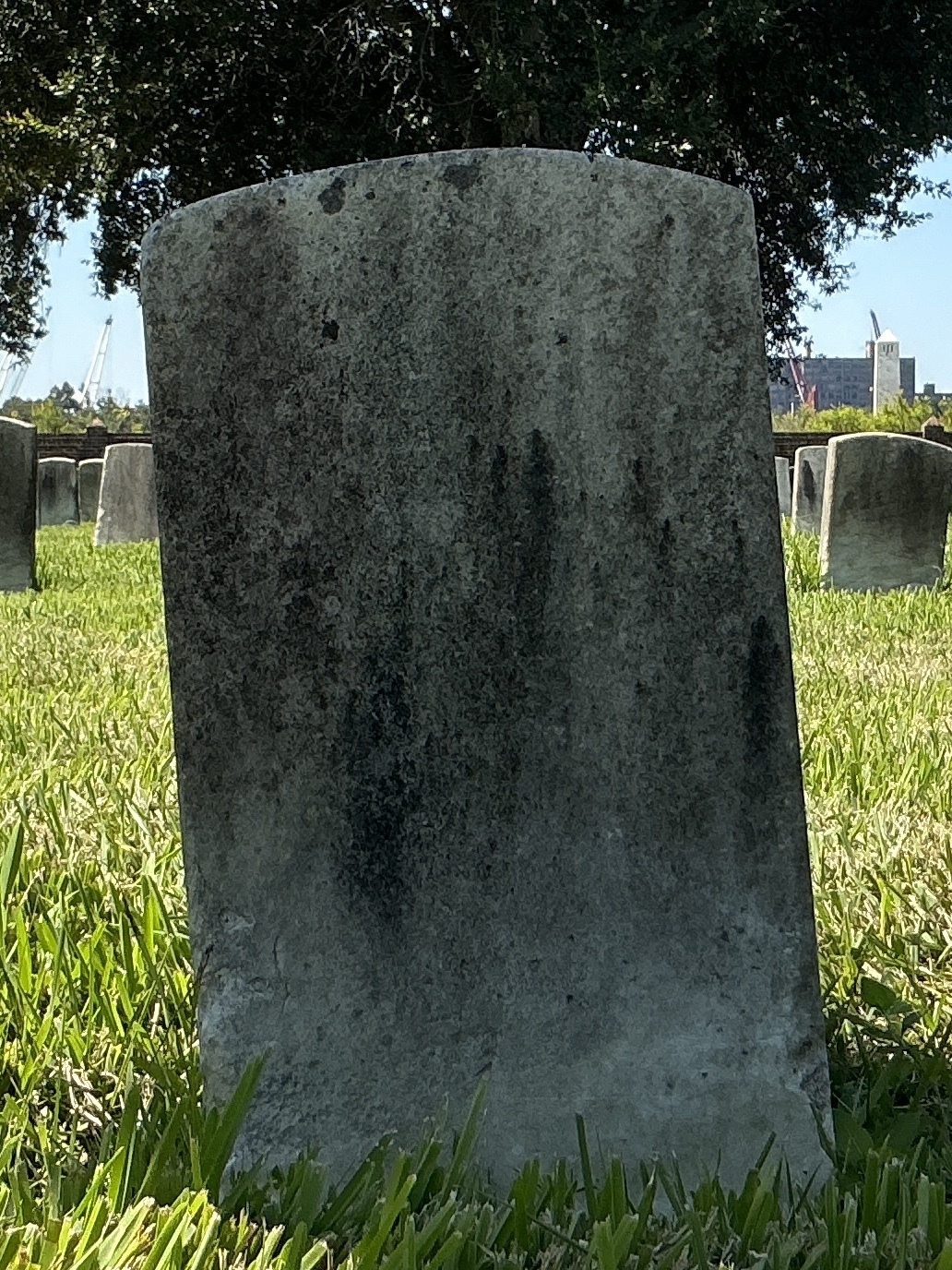 Back of historic upright marble headstone with recessed shield face.