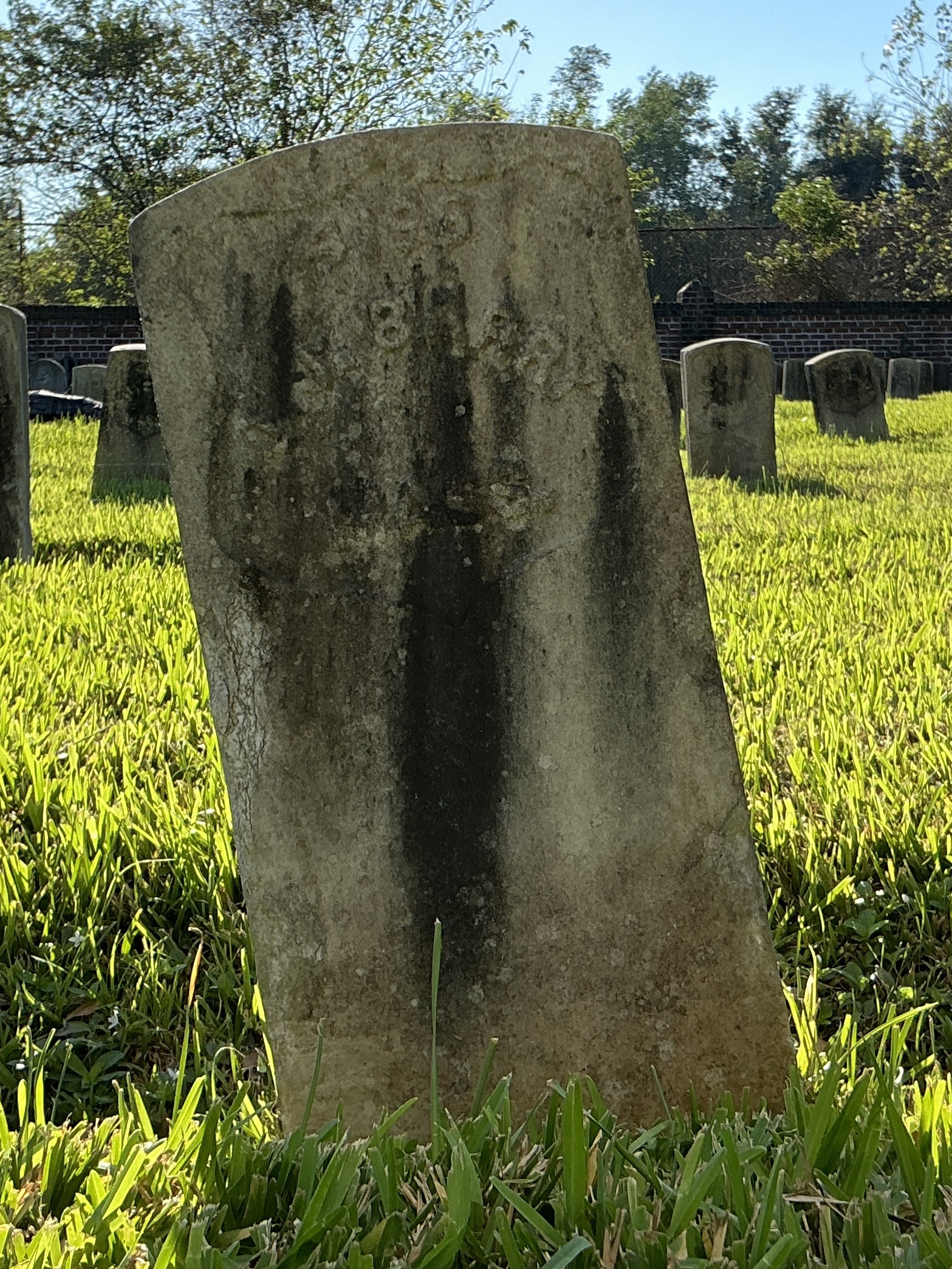 Front of historic upright marble headstone with recessed shield face.