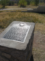 A metal plaque sits on top of a rock in a field.