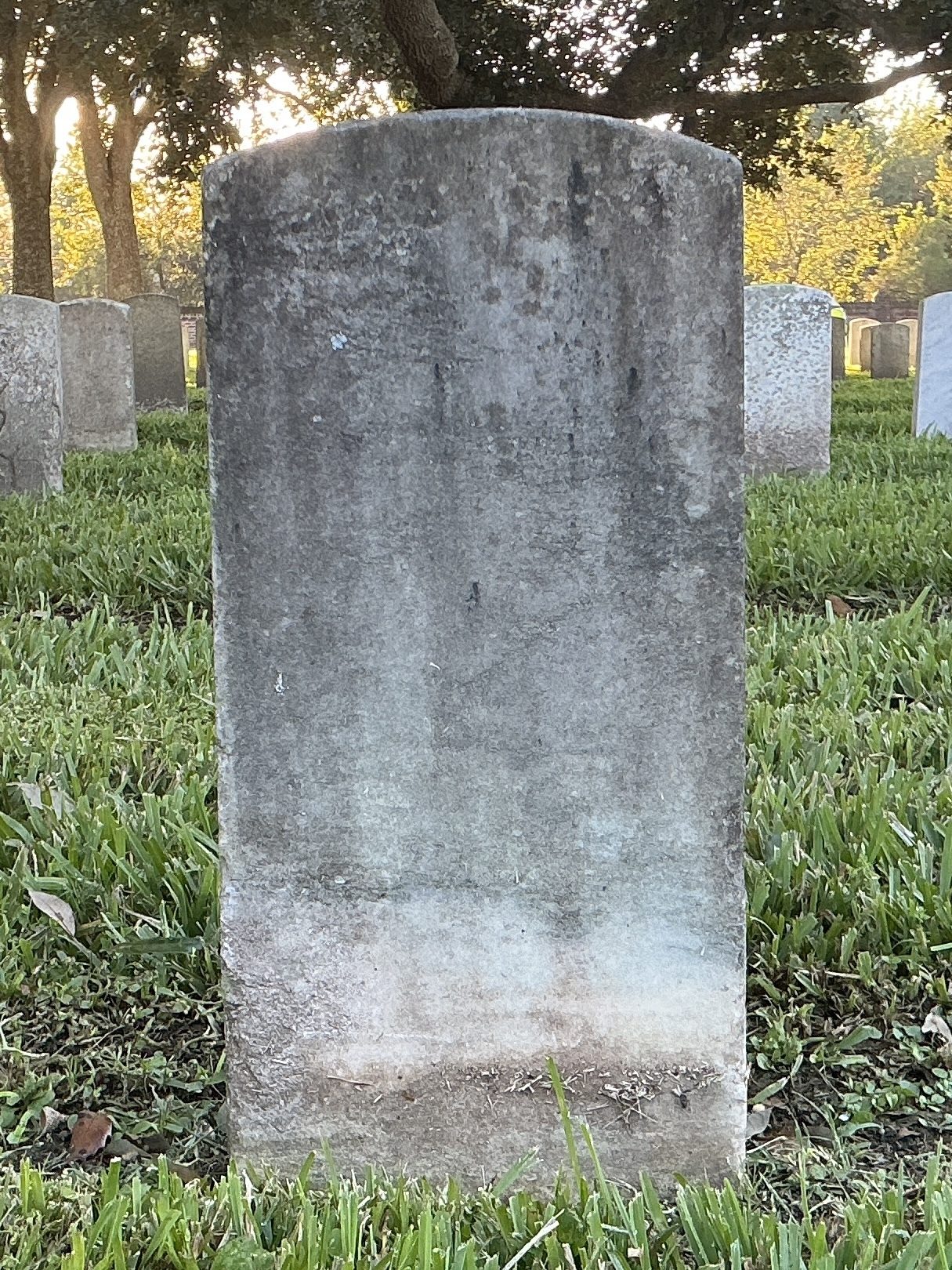Back of historic upright marble headstone with recessed shield face.