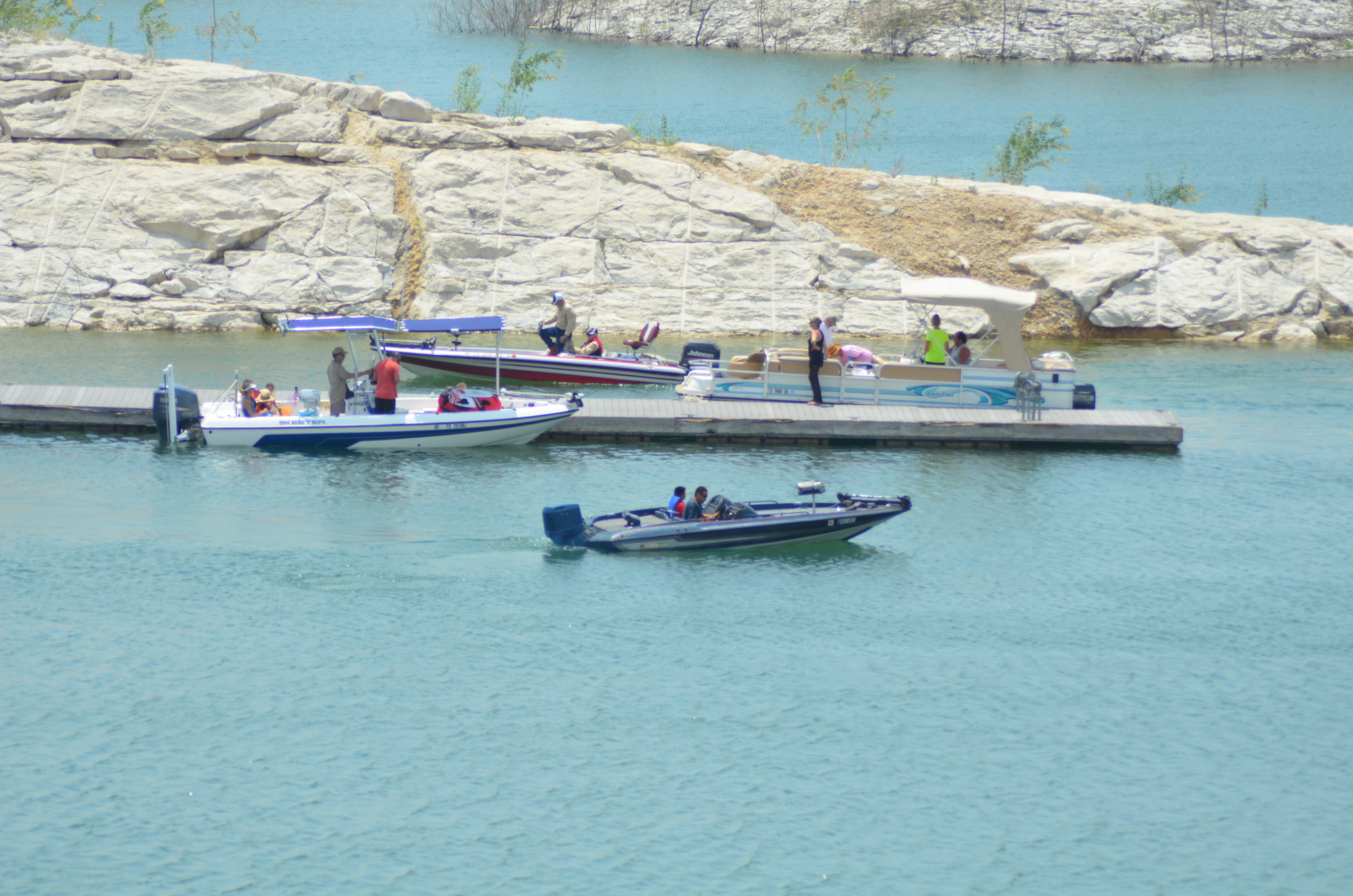 Four boats loading and unloading on a dock on the lake