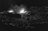 Black and white image of two fountains overflowing at its edge at night.