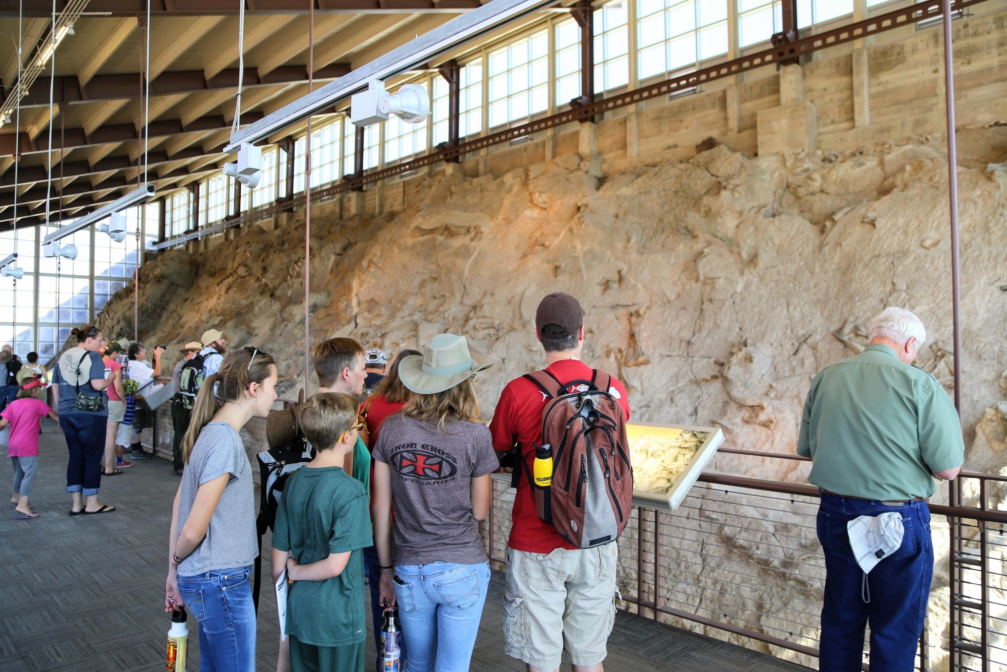 A view of the Quarry Exhibit Hall's upper floor. A crowd of visitors observes the Wall of Bones from the railing.