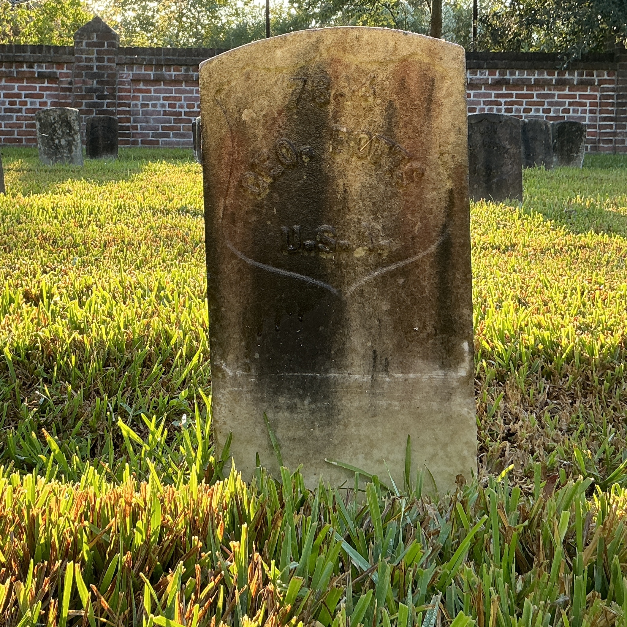 Front of historic upright marble headstone with recessed shield face.