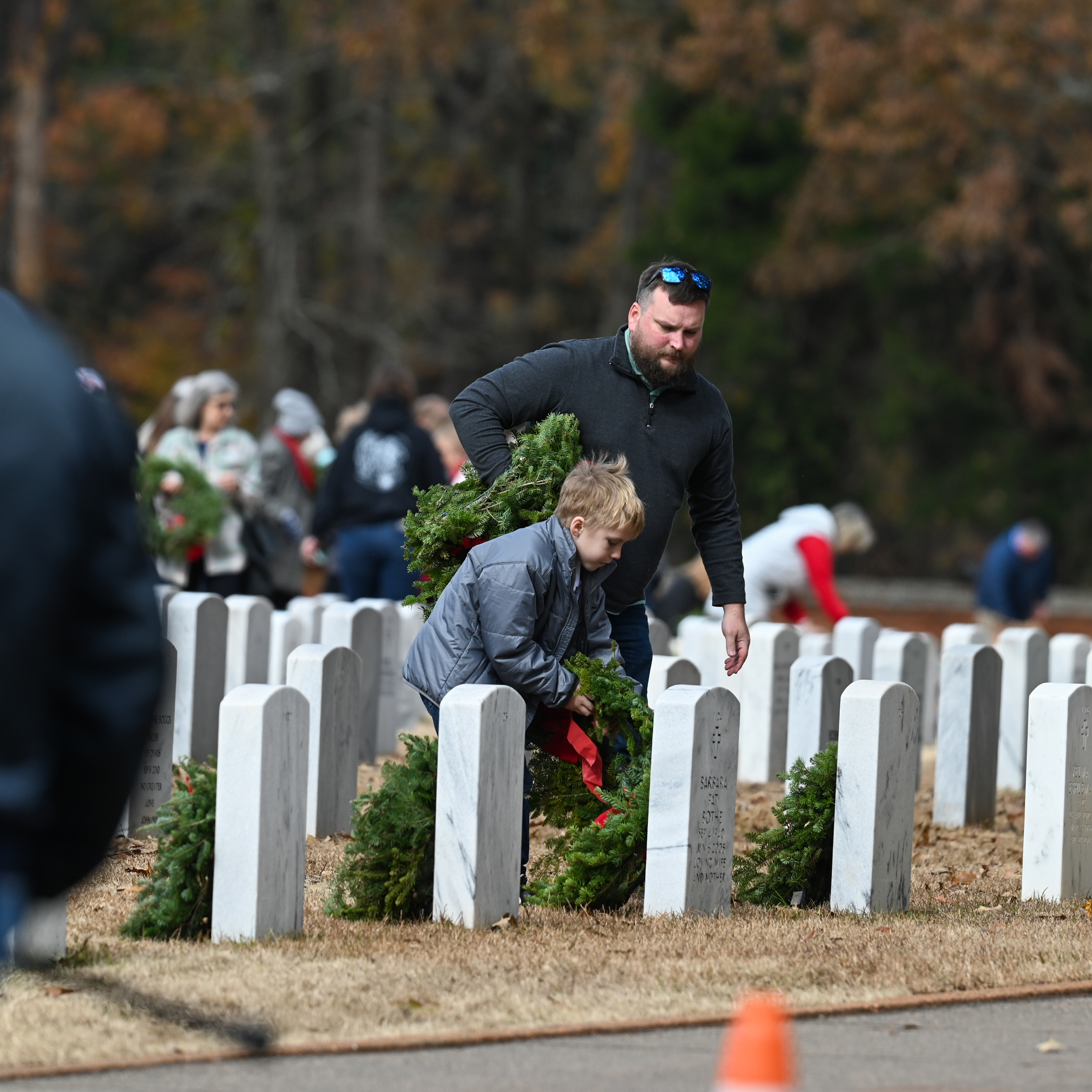 Volunteers placing wreaths in front of headstones.