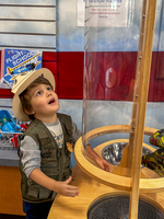 A small child looks up towards the top of a clear tube. 