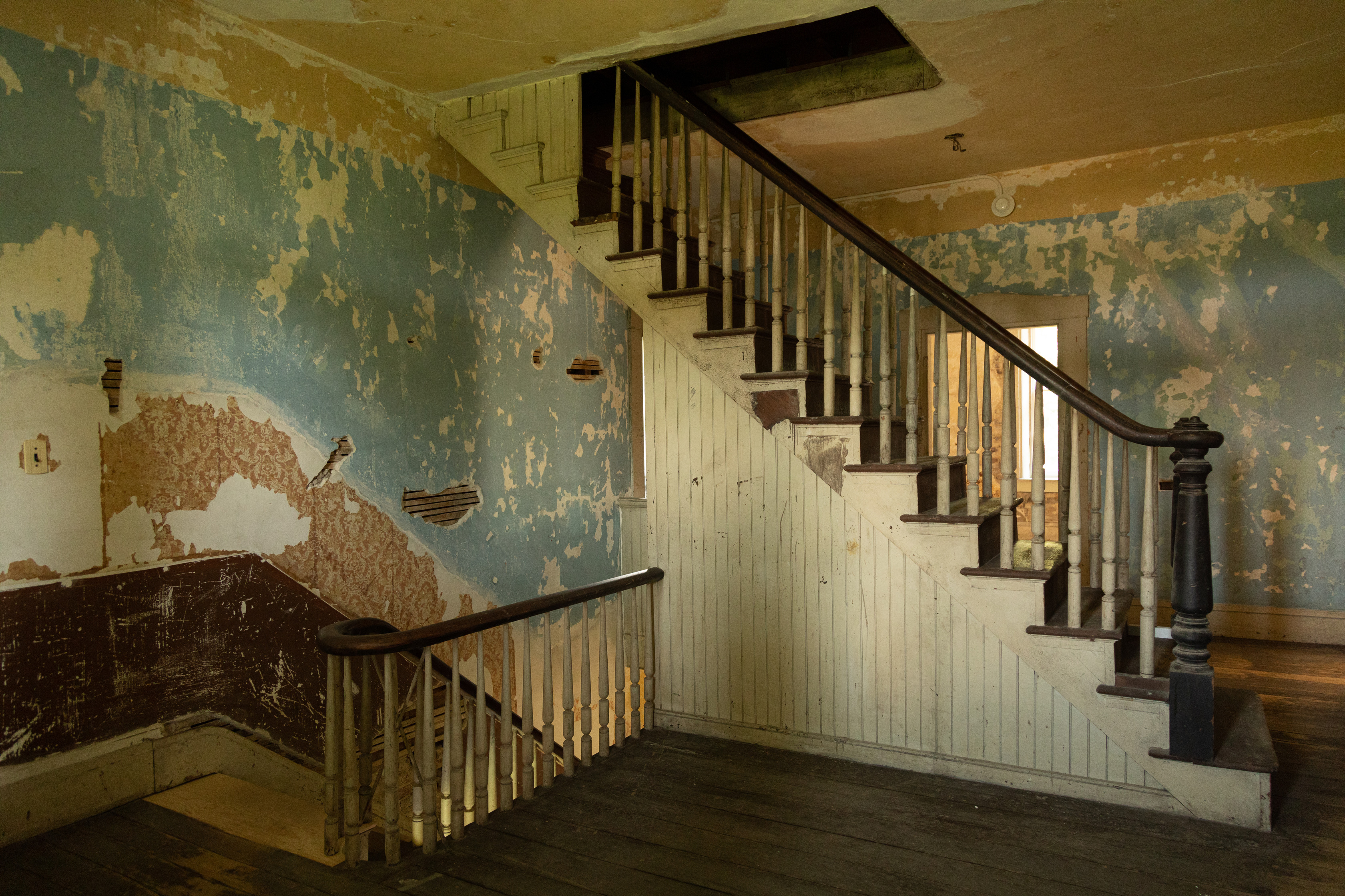 This space contains the staircase leading up from the first floor and a separate staircase providing access to the attic. The walls have plaster surfaces, stud framed with machine-made lath holding the plaster. Along the top of the walls, a paint boundary forms a border area. Flooring in the passageway consists of tongue and groove boards, blind nailed, with no joints over the span of the room. 