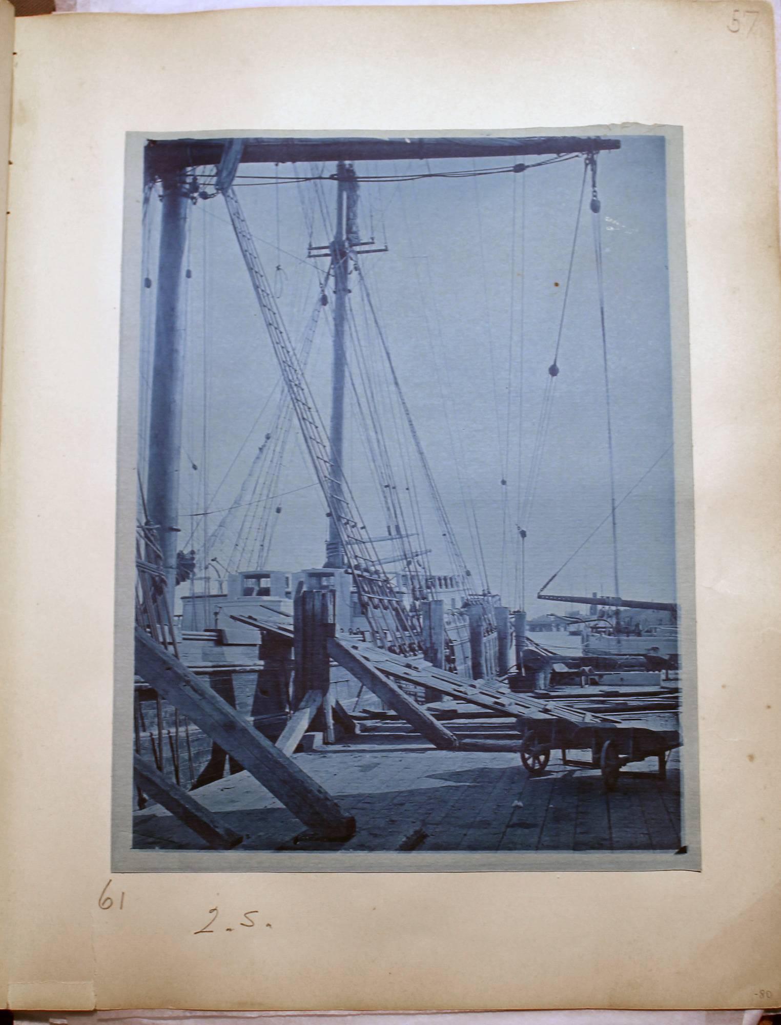 Blue toned photo of tall ship at dock.  Ramp placed on top of railing.