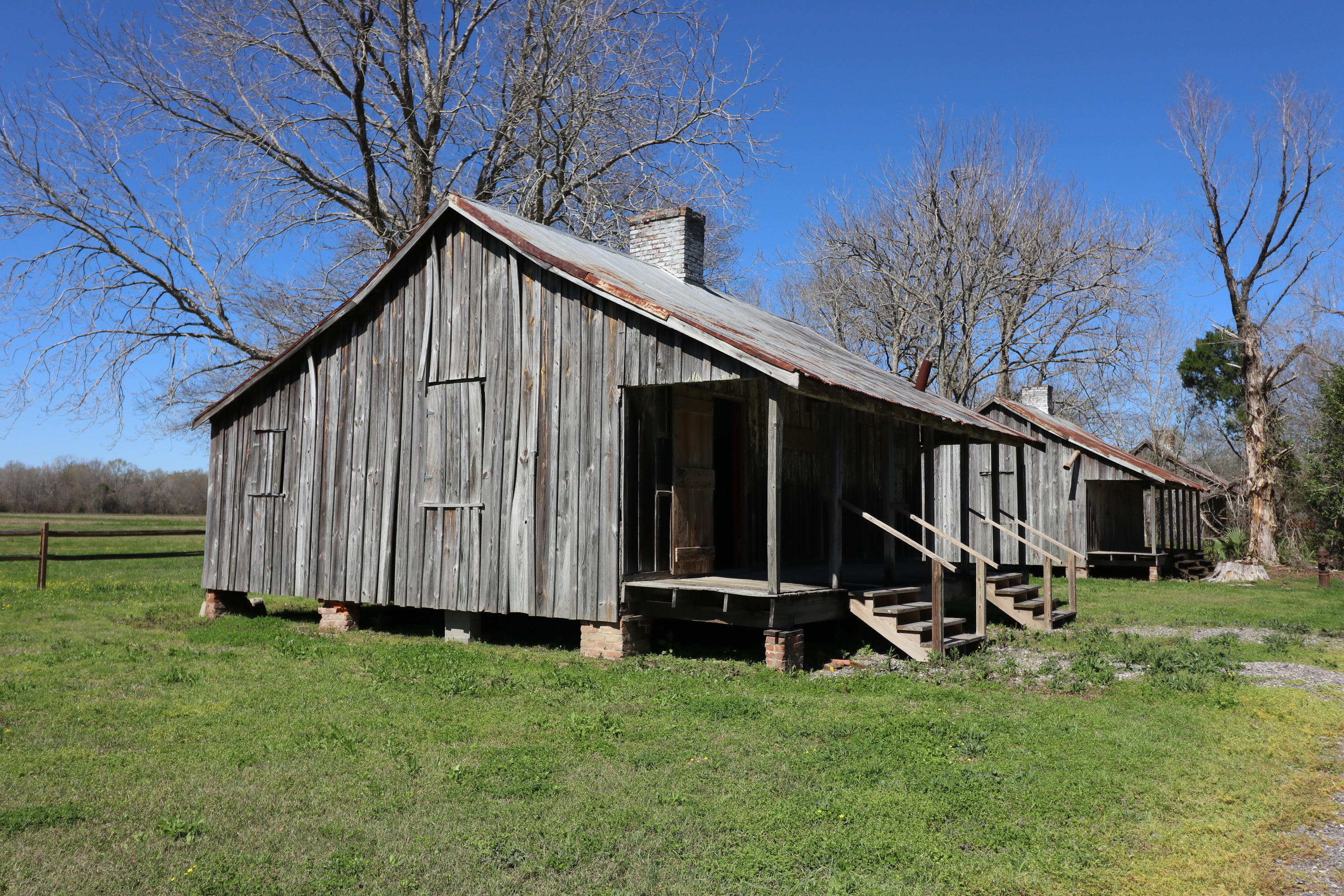 Wooden structure with metal roofing, centralized chimney, and front porch.