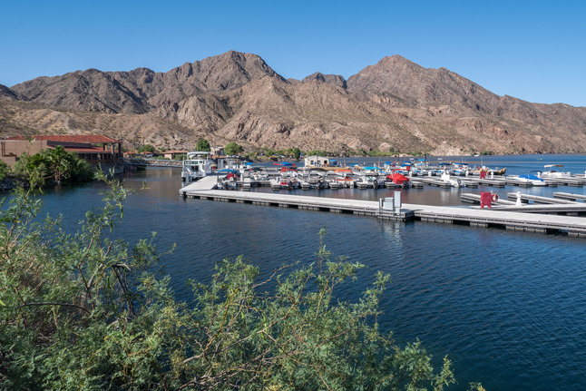 Mesquite trees in lower left with marina and desert mountains in background