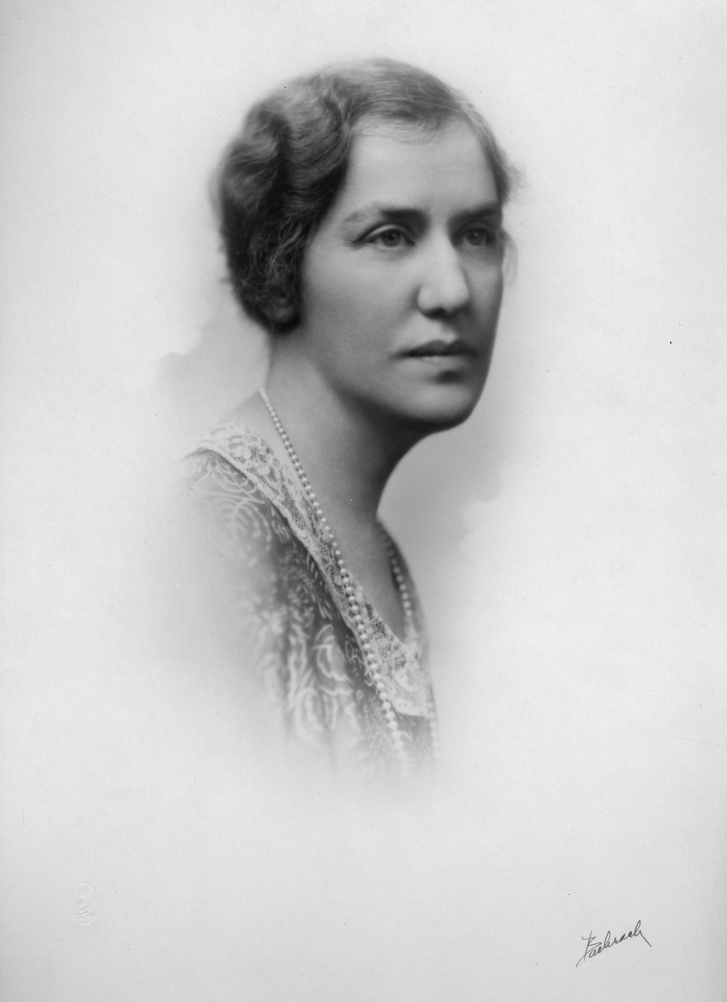 Photo of a woman wearing pearls and looking away from the camera. 