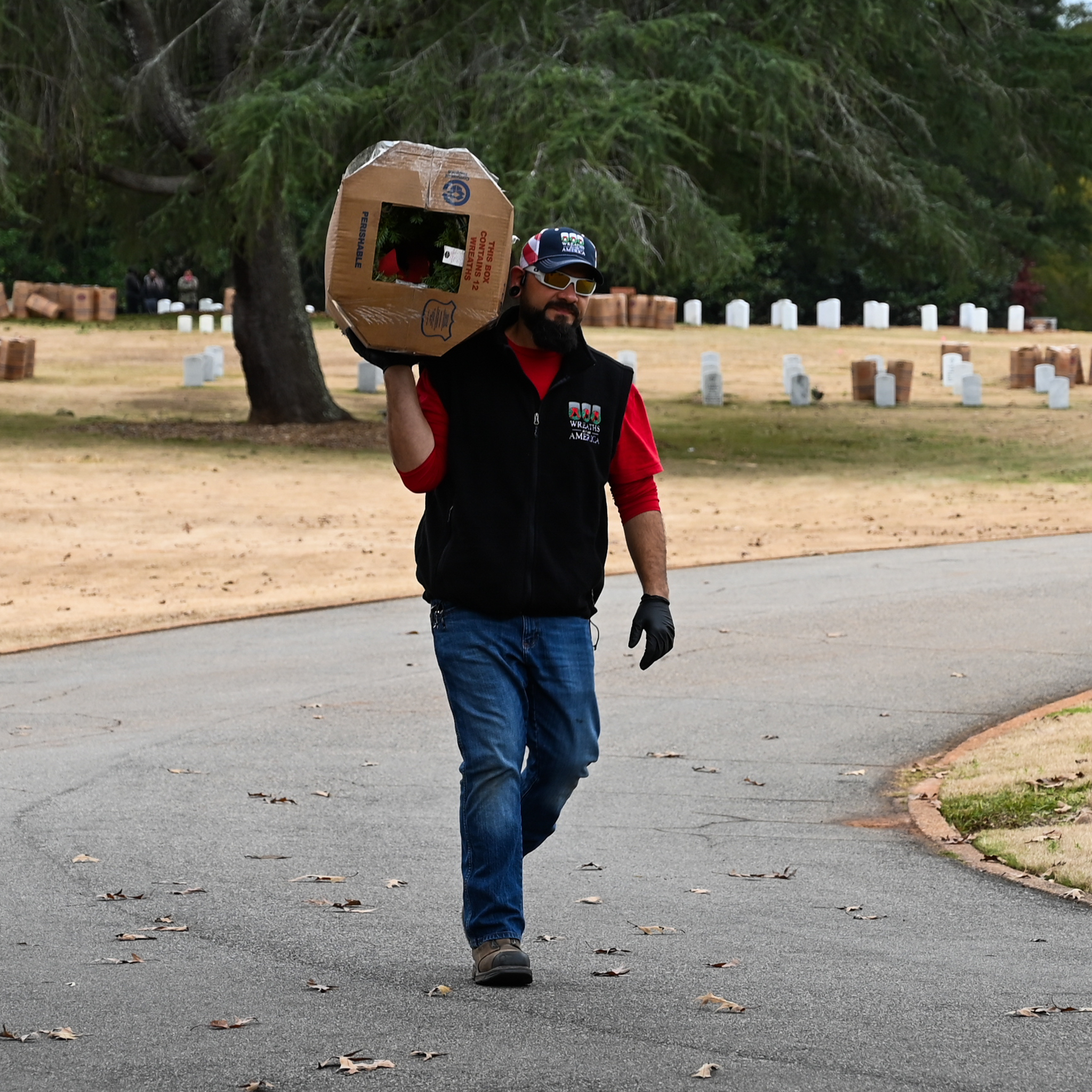 Volunteer carrying a box of wreaths over his shoulder.