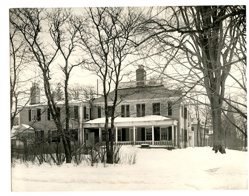 Black and white photograph of side facade of Georgian mansion and ell in snow.