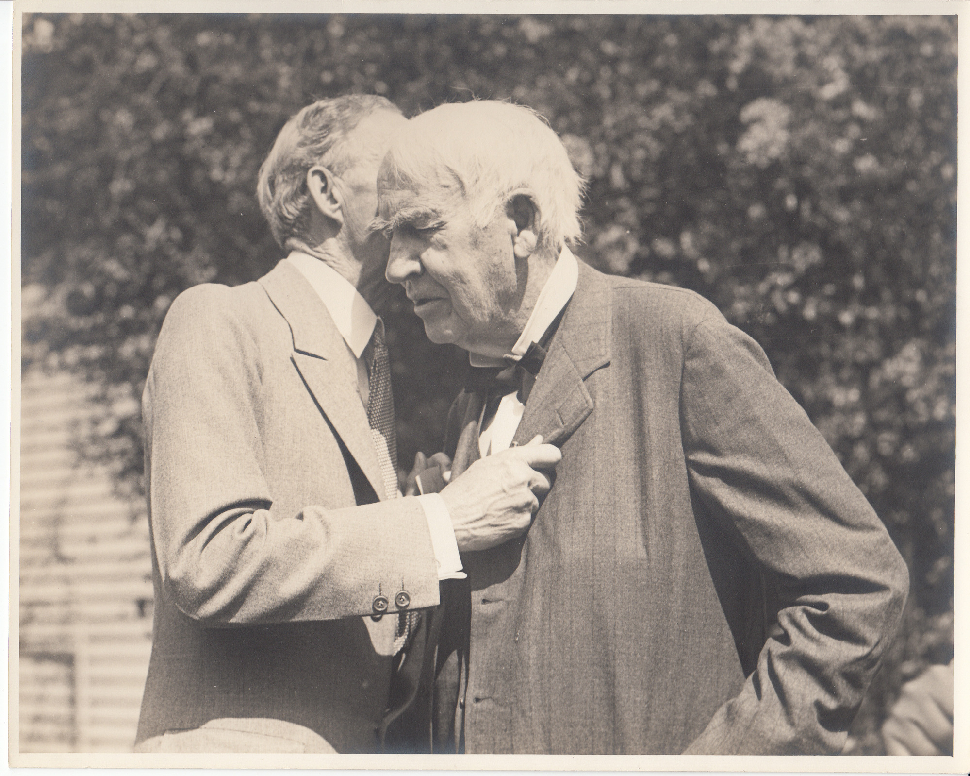 Henry Ford speaking into Thomas Edison's right ear.