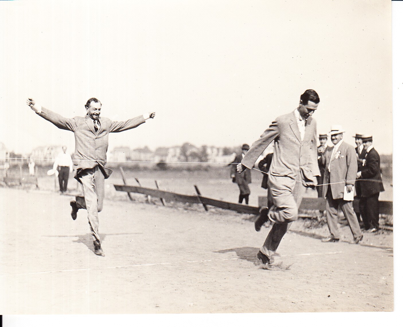 Runners in the executive race crossing finish line at Edison field day, held at Olympic Park.  Nelson Durand is at left.