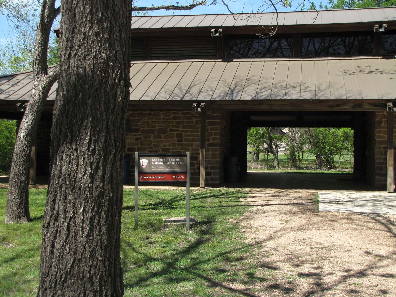 A large, stone building with a two-tiered roof and a wide, dark breezeway has a national historical park sign out front.